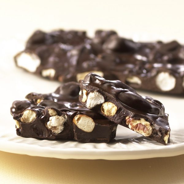 Dark Chocolate Boardwalk crunch is creamy chocolate coated popcorn, marshmallows, nuts, and salted pretzels on white plate.