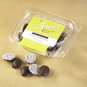 Dark Chocolate Nonpareils clear Fresh Pack with yellow and white Asher's Chocolate Co. Label. Six (6) dark chocolate drops are scattered outside of Fresh Pack to reveal size, color, and texture.