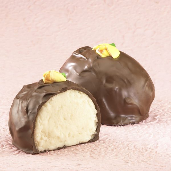 16-oz Milk Chocolate Vanilla Butter Cream Eggs with edible yellow decorative flowers on top. One (1) Egg cut in half to reveal white inside. Other egg whole in background. Pictured on light purple backdrop.