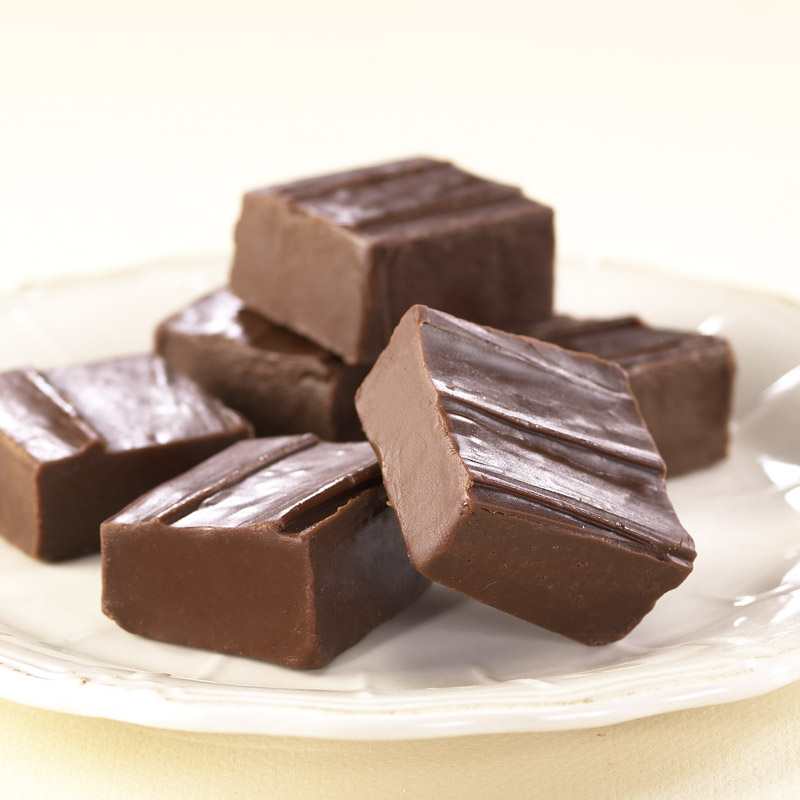 Asher's Chocolate Co. Chocolate Fudge cut into cubes and stacked on a white plate.
